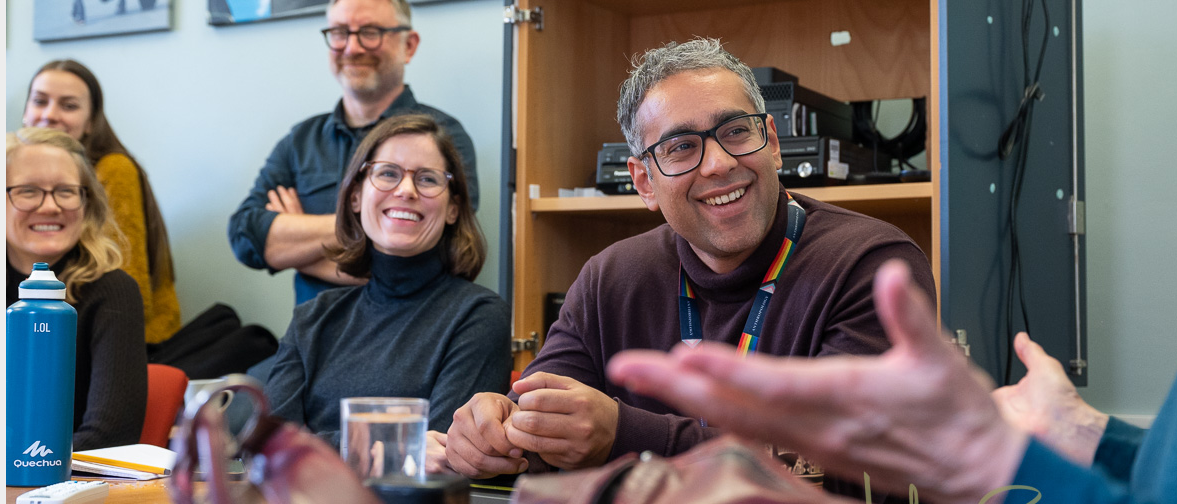 Members of the team sitting around a table enjoying conversation. 