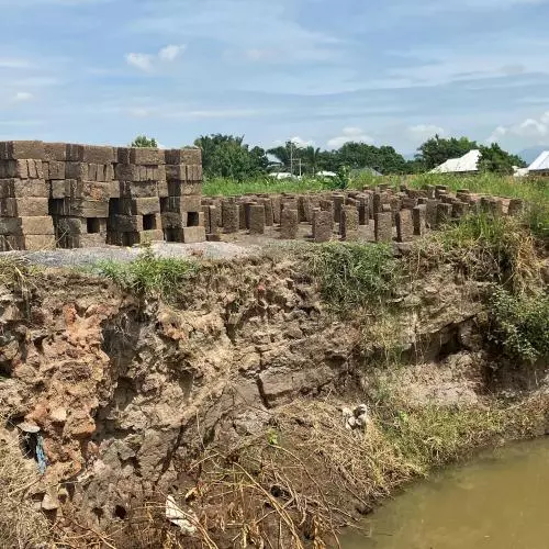An image showing a pile of bricks next to a river.