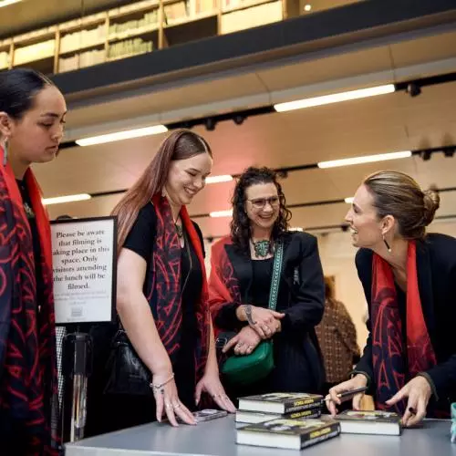 (Right) Dame Jacinda Ardern, former Prime Minister of New Zealand, signs books for visitors attending the lunch at the Weston Library. 