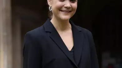 A woman in a black jacket outside an old stone building