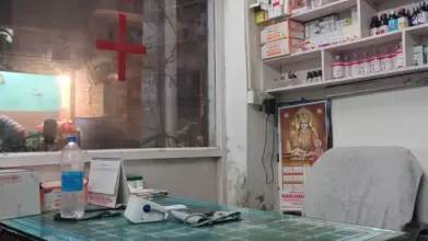 a makeshift office with a red cross on the window and medicines displayed behind the desk.