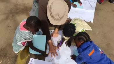 View of a group from above - children are drawing around a mans hand