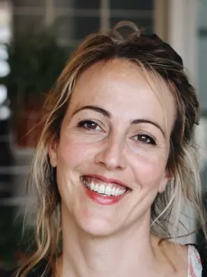 Dr Alex Alvergne is smiling at the camera with a wide smile. 