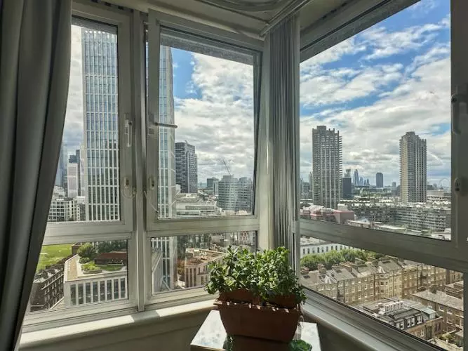 View from a living room's corner window showing sky scrapers and tower blocks on a sunny day