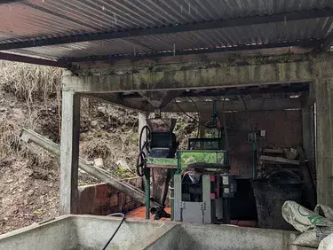 A roofed beneficiadero, where harvested coffee cherries are brought for processing, at the Bellavista farm, in a vereda (rural district) of the municipality of Arboledas, Norte de Santander. In the foreground are two cement fosas (basins); in the backgrou