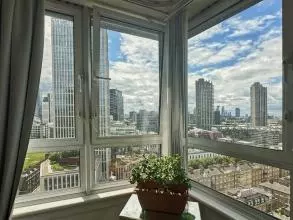 View from a living room's corner window showing sky scrapers and tower blocks on a sunny day