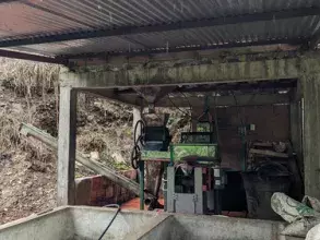 A roofed beneficiadero, where harvested coffee cherries are brought for processing, at the Bellavista farm, in a vereda (rural district) of the municipality of Arboledas, Norte de Santander. In the foreground are two cement fosas (basins); in the backgrou