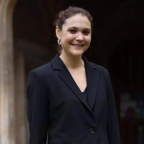 A woman in a black jacket outside an old stone building