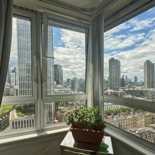 View from a living room's corner window showing sky scrapers and tower blocks on a sunny day