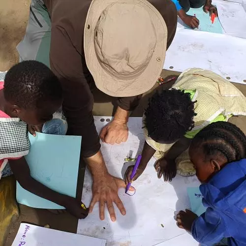 View of a group from above - children are drawing around a mans hand