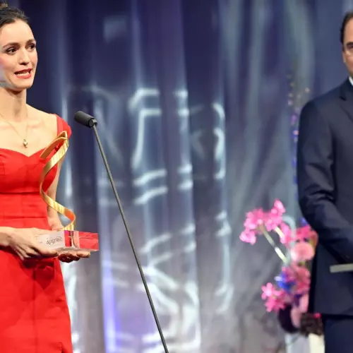Woman in red dress collecting award on stage