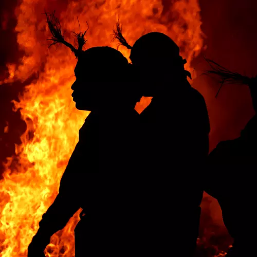 Figures in headdresses silhouetted against a large fire