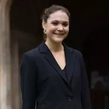 A woman in a black jacket outside an old stone building