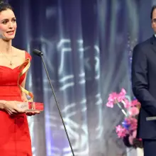 Woman in red dress collecting award on stage