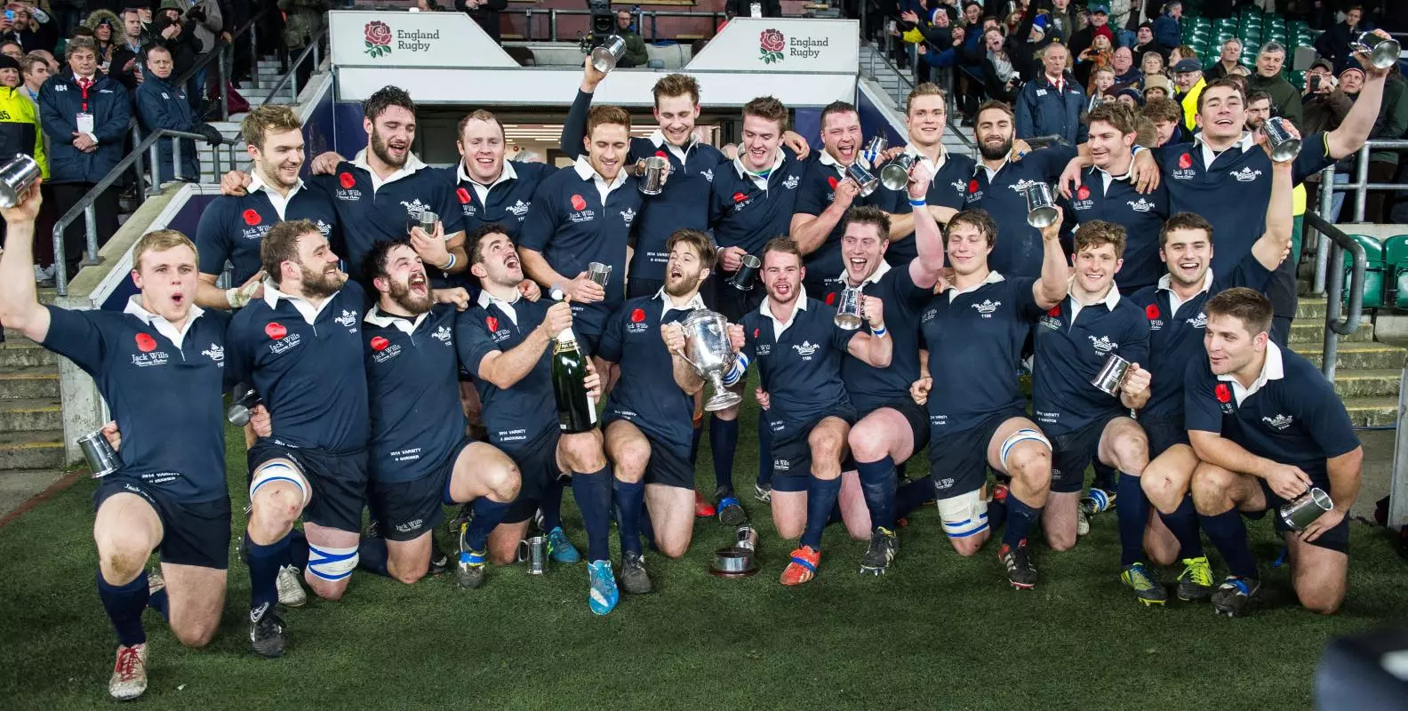 A male rugby team celebrating with a trophy and champagne