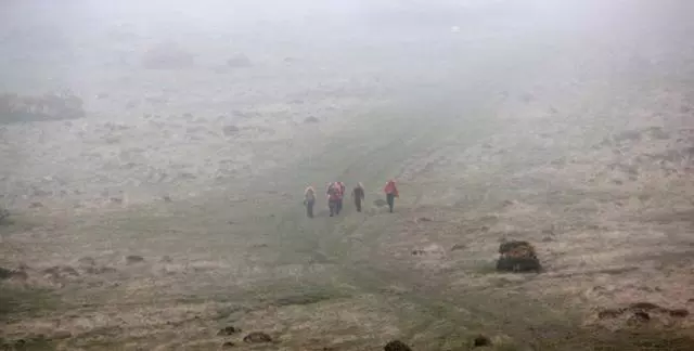 5 hikers in the distance on a misty, grey moor