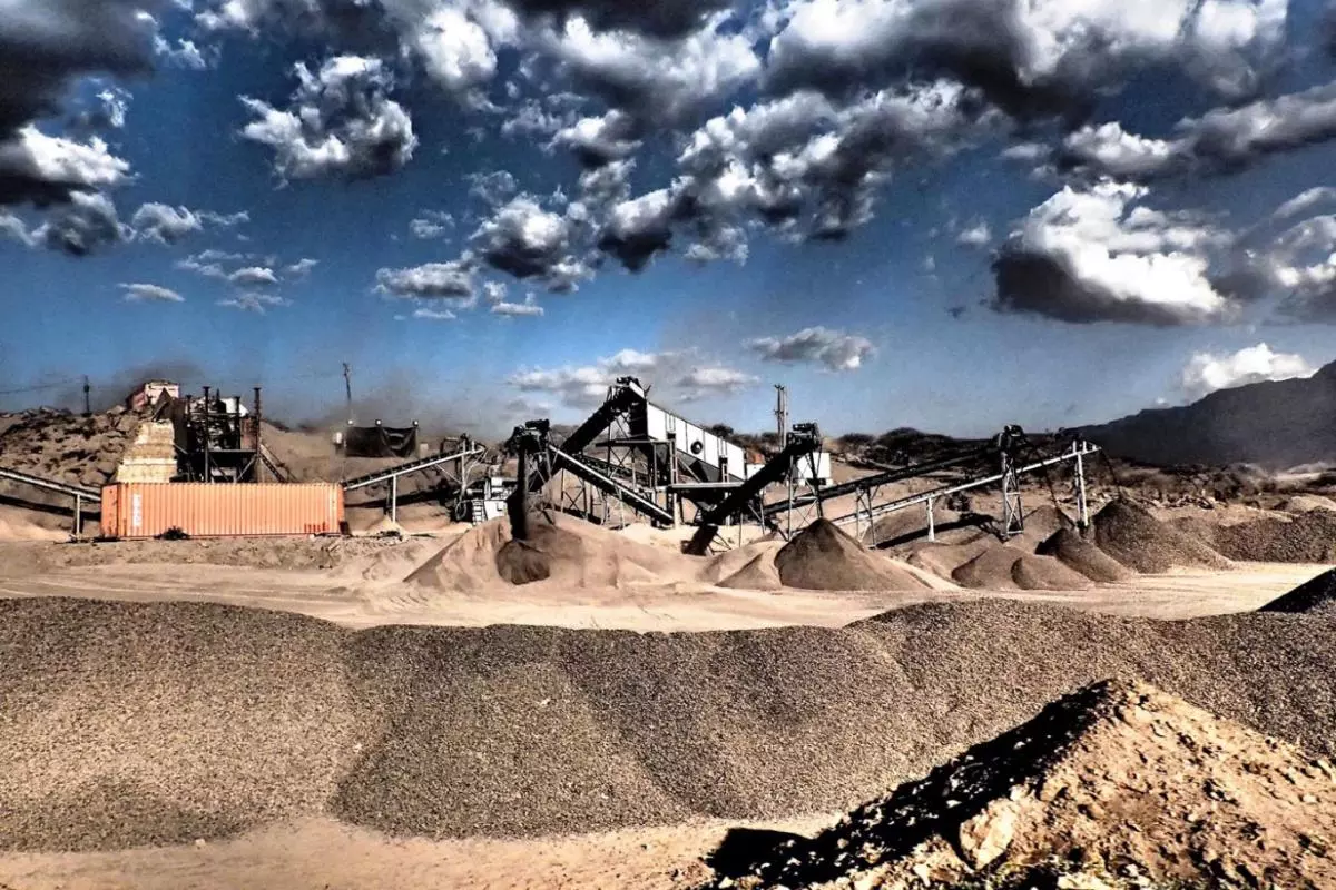 Gravel pit with machinery in sunny arid mountainous region