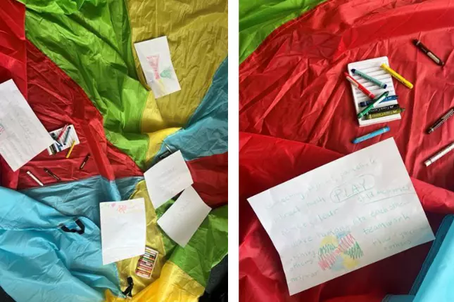 colourful parachute with crayons and paper laid out on the floor
