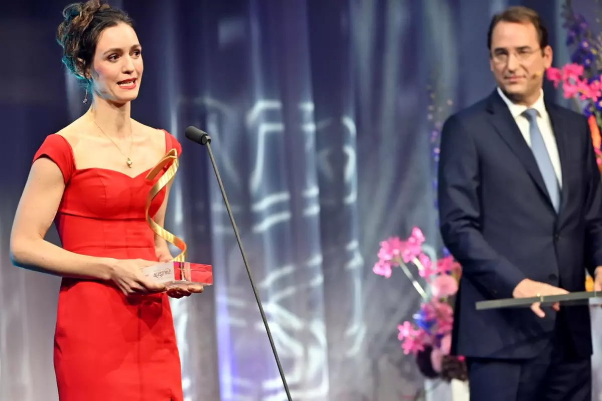 Woman in red dress collecting award on stage